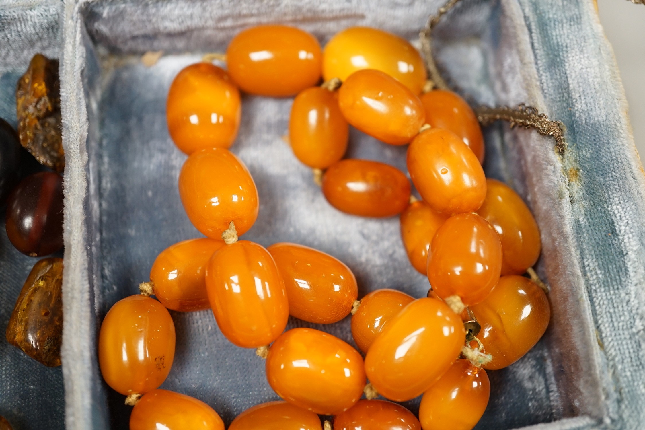 A single strand amber bead necklace, 48cm, gross 52 grams, together with other loose amber and amberoid beads and an amber pendant in a simulated book box.